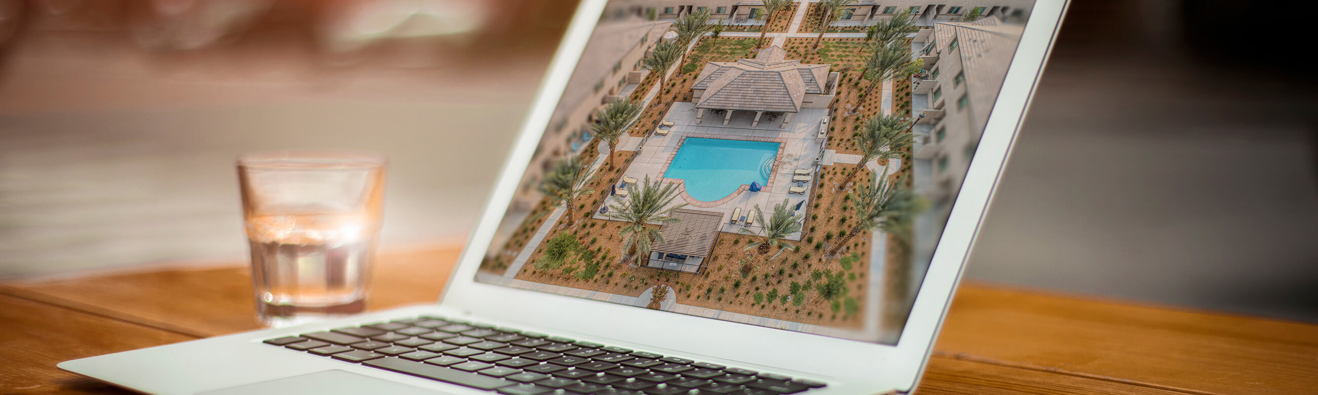 laptop computer with an arial view of a clubhouse and pool on the screen