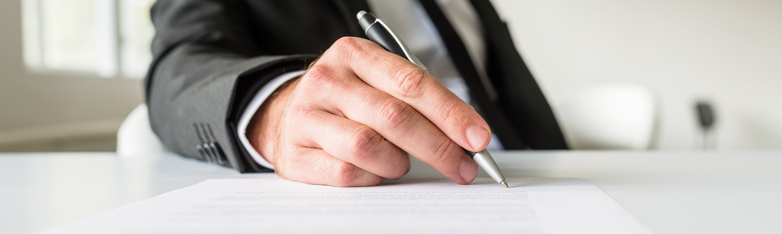 man in a suit holding a pen and writing